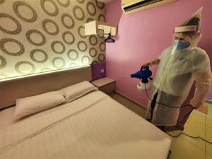 a person standing next to a bed in a room at De UPTOWN Hotel @ P.J. 222 in Petaling Jaya