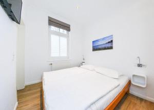 a white bedroom with a white bed and a window at Villa Eden Binz Typ 6 / Apartment 1 in Binz