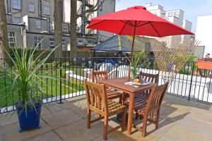 a wooden table with two chairs and a red umbrella at Gresham 1-bed in Eastbourne