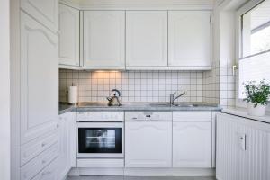 ヴェニングシュテットにあるAppartement-Rivaの白いキッチン(白いキャビネット、シンク付)