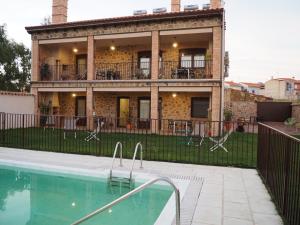 una casa con piscina frente a ella en Apartamentos rurales Posada de Monfragüe con jacuzzi en Malpartida de Plasencia