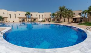 una gran piscina de agua azul frente a un edificio en Simaisma A Murwab Resort, en Sumaysimah