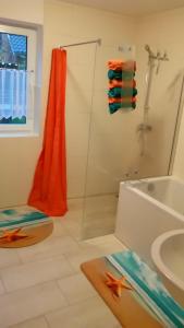 a bathroom with a shower with an orange shower curtain at Haus-Hempel-1 in Groß Mohrdorf
