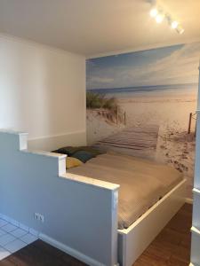 Bett in einem Zimmer mit einem Wandbild eines Strandes in der Unterkunft 50 m zum Strand - App Strandhuepfer - Saisonstrandkorb inklusive in Timmendorfer Strand