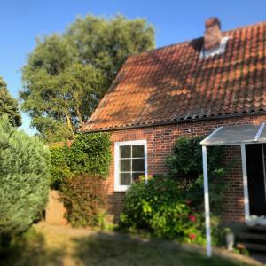 une maison en briques avec une fenêtre et un toit dans l'établissement Schoenes-Ferienhaus-mit-Garten-Mid-Century-Moebeln-in-Strand-naehe-Avendorf, à Avendorf auf Fehmarn