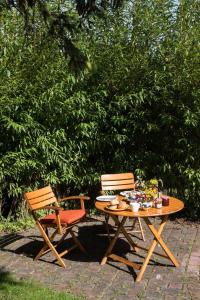 a picnic table and two chairs sitting next to a bush at Schoenes-Ferienhaus-mit-Garten-Mid-Century-Moebeln-in-Strand-naehe-Avendorf in Avendorf auf Fehmarn