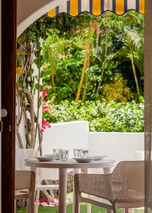 een tafel en stoelen met een tuin op de achtergrond bij Apartments Parque Santiago IV in Playa de las Americas