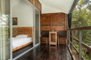 a bedroom with a bed and two chairs on a balcony at Beu Ceubeh Cottage Sabang in Sabong
