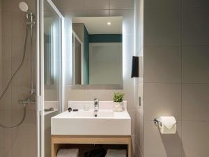 a bathroom with a white sink and a mirror at Adagio access Brussels Delta in Brussels