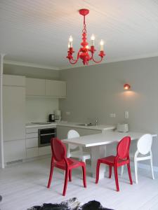 cocina con mesa, sillas rojas y lámpara de araña en Bungalow-L, en Westerland 7 fotos más