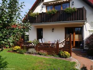 ein Haus mit einem Balkon mit Stühlen und Blumen in der Unterkunft Ferienwohnung "  An der Koppel " in Mölln-Medow