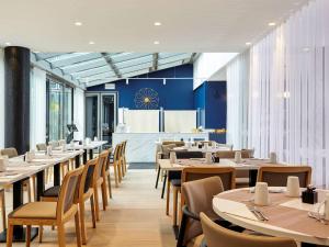 una sala da pranzo con tavoli, sedie e un bar di Mercure Paris la Défense Grande Arche a Nanterre