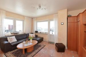 a living room with a black leather couch and a table at Wohnung-Lee in Westerland (Sylt)