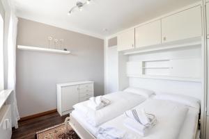 a white bedroom with a white bed and white cabinets at Wohnung-Lee in Westerland (Sylt)