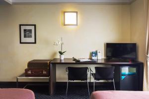 ミラノにあるHotel Colombiaの机と椅子2脚、テレビのある部屋