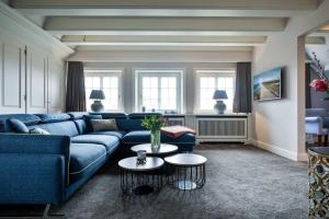 a living room with a blue couch and two tables at Suite Die 12 in Kampen