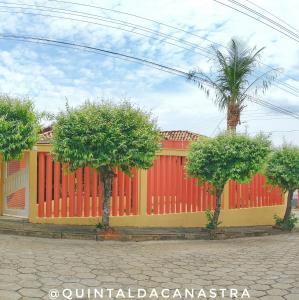 um edifício vermelho e amarelo com árvores em frente em Casa com piscina - 3 quartos - Centro em São João Batista do Glória
