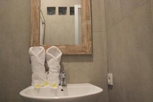 a bathroom with a sink with a mirror and towels at EUFORIA Guest House in Canggu