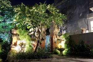 a garden with trees and plants in front of a building at EUFORIA Guest House in Canggu