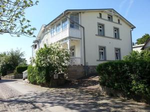 ein großes weißes Haus mit Büschen davor in der Unterkunft Villa Rosengarten - Ferienwohnung Terra in Sassnitz