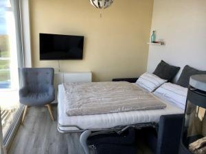 a room with a bed and a couch and a tv at MEHS46A21-FeWo-Best-Kiekout in Meeschendorf