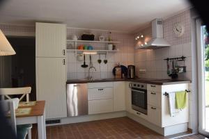 a kitchen with white cabinets and a sink and a refrigerator at Bungalow-Gartenzauber in Grube
