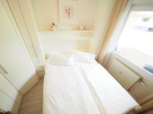 uma cama branca num quarto com uma janela em Appartement-167 em Westerland