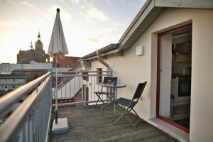 einen Balkon mit einem Tisch, Stühlen und einem Sonnenschirm in der Unterkunft Haus Steuerrad in Stralsund