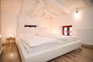 Cama blanca grande en habitación con suelo de madera en Haus Steuerrad, en Stralsund