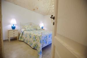 een slaapkamer met een bed en een tafel met een lamp bij Agriturismo Arco di Sole in Alberobello