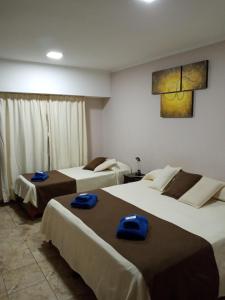two beds in a hotel room with blue towels on them at Hotel Silver Golf in Sierra de la Ventana