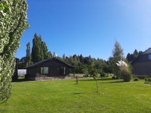 a small cabin in a grassy yard with trees at Viento y montaña in San Carlos de Bariloche
