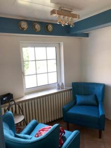 a living room with two blue chairs and a window at Haus Frisia Ferienwohnung Frisia 6 in Norddorf