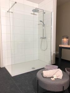 a bathroom with a shower and a stool with a towel at Huis Berenbroek in Genk