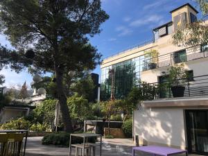a building with tables and a tree in front of it at Appart' Hotel La Girafe Marseille Est - Porte d'Aubagne in La Penne-sur-Huveaune