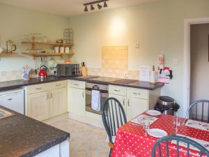 una cocina con una mesa con un mantel rojo. en Beechwood Cottage en Pitlochry
