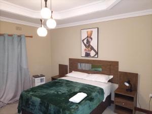 a bedroom with a large bed with a green blanket at Semuya Apartments in Ndola