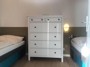 a bedroom with a white dresser next to two beds at 50-Meter-bis-zum-Strand-Luetje-Loge in Timmendorfer Strand