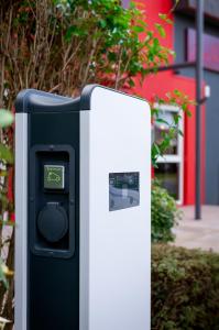 a parking meter in front of a red building at Zenith Hotel Caen in Caen