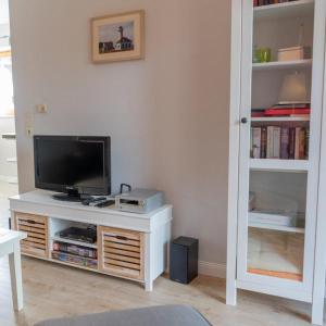 - un salon avec une télévision sur un centre de divertissement blanc dans l'établissement Ferienwohnung-Stinson-Beach, à Lemkenhafen auf Fehmarn