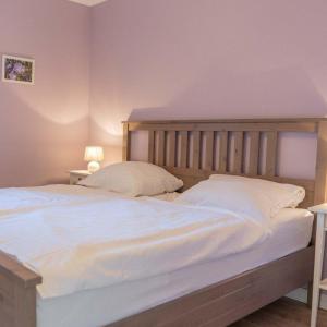 - une chambre dotée d'un grand lit avec des draps et des oreillers blancs dans l'établissement Ferienwohnung-Stinson-Beach, à Lemkenhafen auf Fehmarn