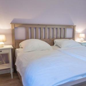 - un lit avec des draps et des oreillers blancs dans une chambre dans l'établissement Ferienwohnung-Stinson-Beach, à Lemkenhafen auf Fehmarn