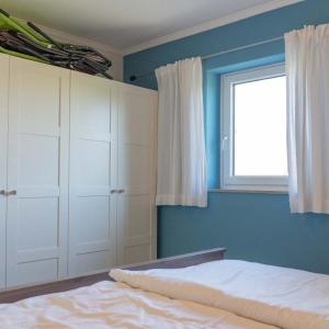 a bedroom with blue walls and a bed and a window at Ruhe-Insel in Lemkenhafen auf Fehmarn