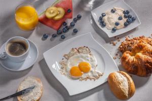 a table with plates of breakfast foods and a cup of coffee at Hotel Weiherhof am Golfpark in Wadern