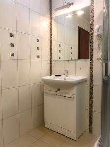 ein weißes Badezimmer mit einem Waschbecken und einem Spiegel in der Unterkunft Alanta "Easy Kaunas" in Kaunas