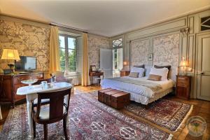 a bedroom with a bed and a table and a tv at Château du Golf de la Freslonnière in Le Rheu +24 photos
