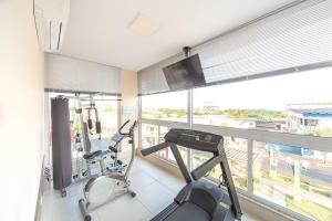 a gym with a treadmill and a flat screen tv at Caligio Hotel in Pirapòzinho