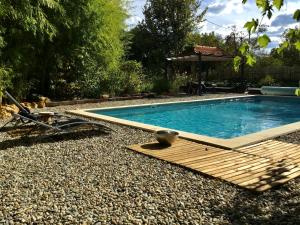 a swimming pool with a wooden boardwalk around it at Villa Léovil in Saint-Pompont