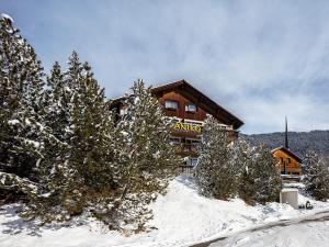 a ski lodge in the snow in front of trees at DANILO Savognin in Savognin