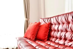 a red leather couch with two red pillows on it at Riverside Inn Hakata in Fukuoka